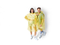 Two smiling people wear transparent yellow raincoats and sneakers.
