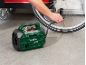 Man inflating bicycle tire with green portable compressor.