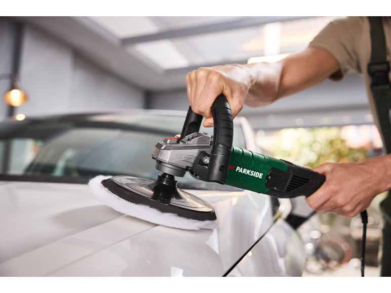 Man polishing a white car with an electric polisher.