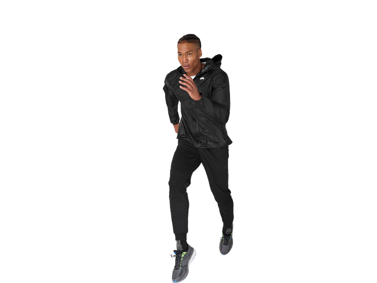 Man running in black jacket, sweatpants, and athletic shoes.