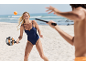 Woman in swimsuit playing beach tennis on the beach.
