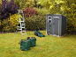 Grey garden shed, lawnmower, and ladder in a green garden.