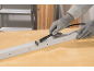 Gloved hands using a rotary tool with a cutting disc to saw a white strip.