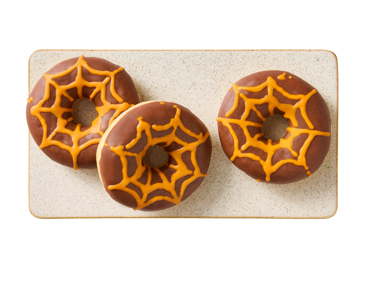 Three chocolate donuts with orange spiderweb icing on a rectangular plate.