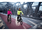 Couple on electric bikes in reflective jackets on a bridge.