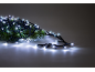 Fir branches with bright white Christmas lights on a grey background.