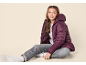 Girl in a purple puffer jacket, grey jeans, and white sneakers.