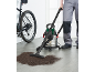 Wet/dry vacuum cleaner cleaning dirt from the floor next to a bicycle.