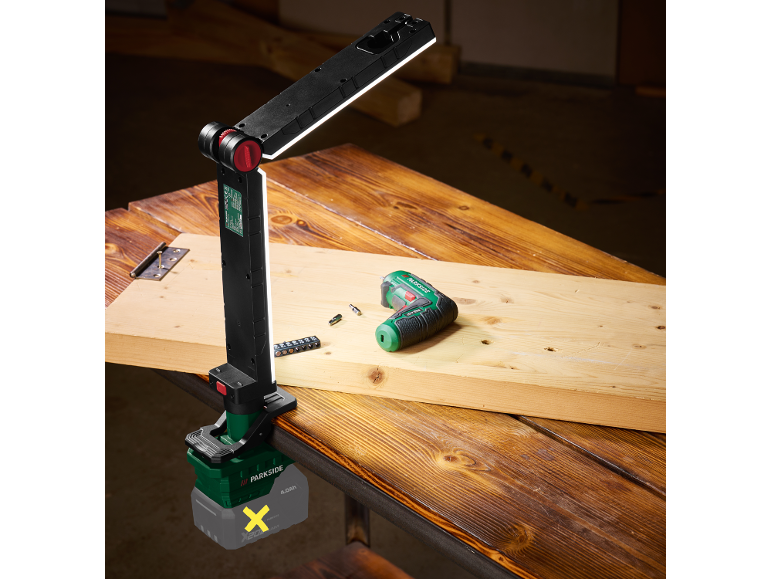 LED battery work light and electric drill on a wooden table.