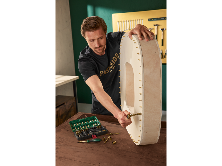 Man assembling a wooden item using a tool set.