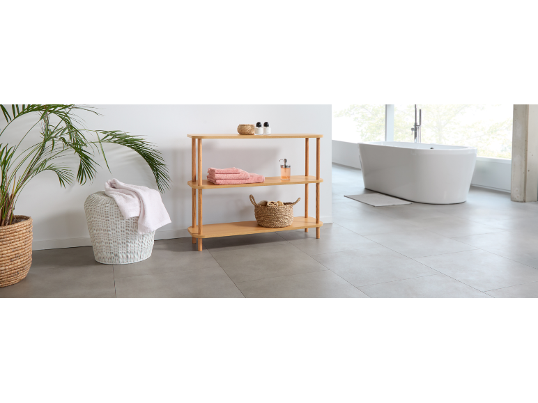 Modern bathroom with a wooden shelving unit, laundry basket, and white bathtub.