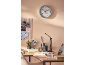Wall clock with thermometer and hygrometer above a desk with a lamp and plants.