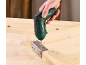 Green and black cordless screwdriver screwing a hinge into a wooden board.