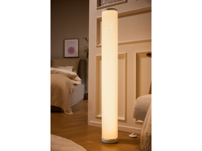 Cylindrical floor lamp with star pattern illuminating a cozy bedroom.
