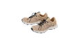 A pair of beige sports shoes with black laces and mesh details.