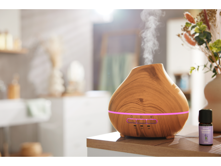 Wooden aroma diffuser with lighting and a bottle of lavender essential oil.