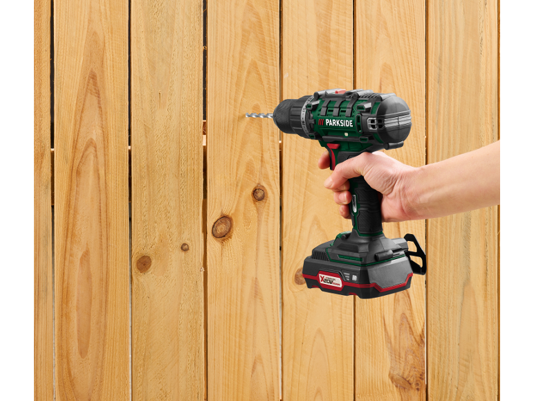 A cordless drill is drilling into a wooden fence.