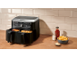 Black dual-basket air fryer with fries and chicken on a wooden surface.