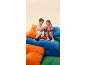Two children in tracksuits and sneakers sit on colorful cushions.