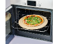 Freshly baked pizza with arugula and prosciutto on a pizza stone inside an open oven.