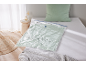 Vacuum storage bag with green bedding on a white bed, with pillow and blanket.