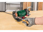 Green grinder with a grinding stone and polishing wheel, sharpening a chisel.