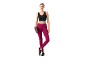 Woman in black sports top and burgundy leggings holding a water bottle.