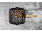 Grilled steak with vegetables in a grill pan on a grey background.