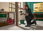 Man using a cordless drill in a workshop, with tools and storage boxes.