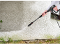 Person cleaning a dirty wall with a pressure washer, removing green algae.