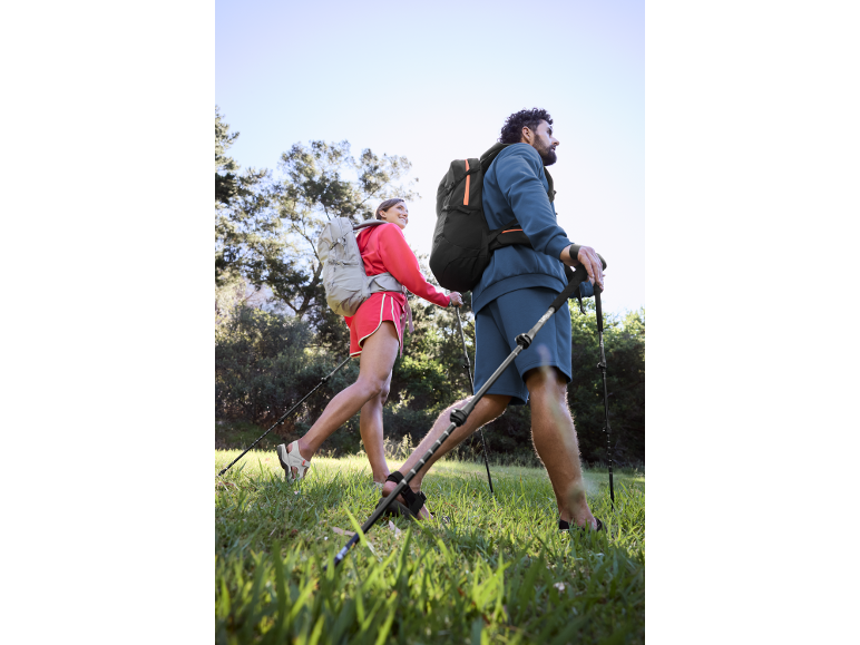 Couple with hiking backpacks and poles enjoying a Nordic walk in nature.