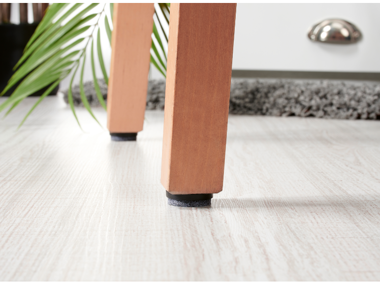 Wooden furniture legs with felt pads on a light wood floor.