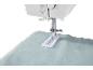 Sewing machine with buttonhole foot on light blue fabric.