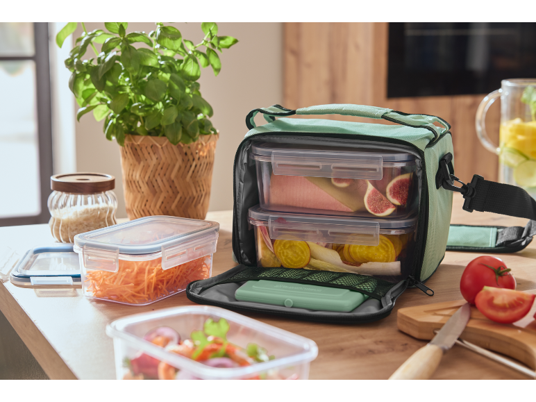 Lunch bag with food containers, including figs and beetroot, on a wooden table.