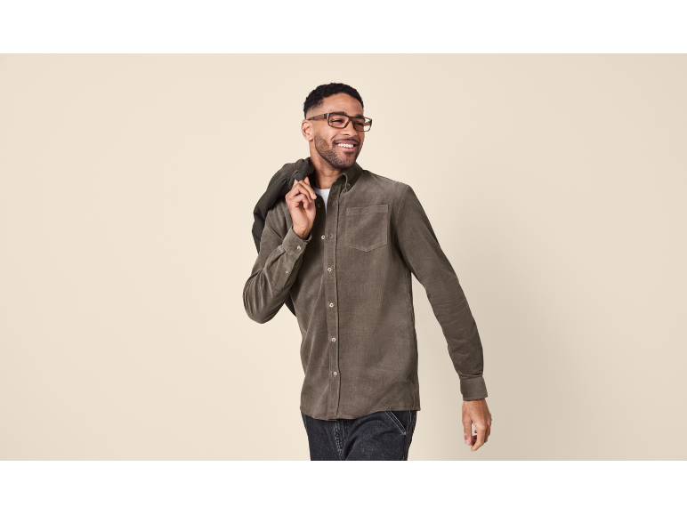 Man in a brown corduroy shirt and glasses, with a jacket over his shoulder.