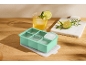 Mint green silicone ice cube tray with lid, drink, and marble cutting board.