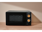 Black microwave with control panel and two wooden dials on a wooden table.