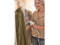 Woman steaming a green shirt with a handheld garment steamer.