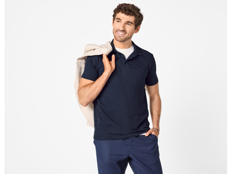 Man in a dark blue polo shirt and trousers, with a jacket over his shoulder.