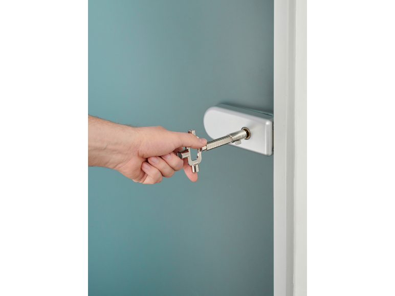 Hand using a service square key to open a door lock.