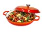 Red cast iron pot with lid, filled with chopped vegetables like zucchini, bell peppers, and onions.