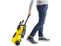 Man pulling a yellow wheeled pressure washer.