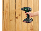 A cordless drill is drilling into a wooden fence.