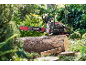 Chainsaw on a tree log outdoors, with a green background.