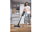 Woman cleaning a wooden floor with a cordless vacuum cleaner with mop function.
