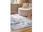 Rug with abstract grey pattern, beige pouf and throw in a living room.
