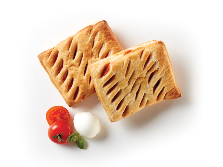 Two savory pastries with cherry tomatoes, mozzarella, and basil on a white background.