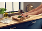 Person chopping parsley on a wooden cutting board in a kitchen.