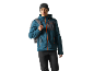 Man in blue jacket with orange zippers, black beanie, and backpack.