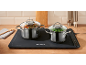 Two pots of food on an electric warming mat on a kitchen counter.